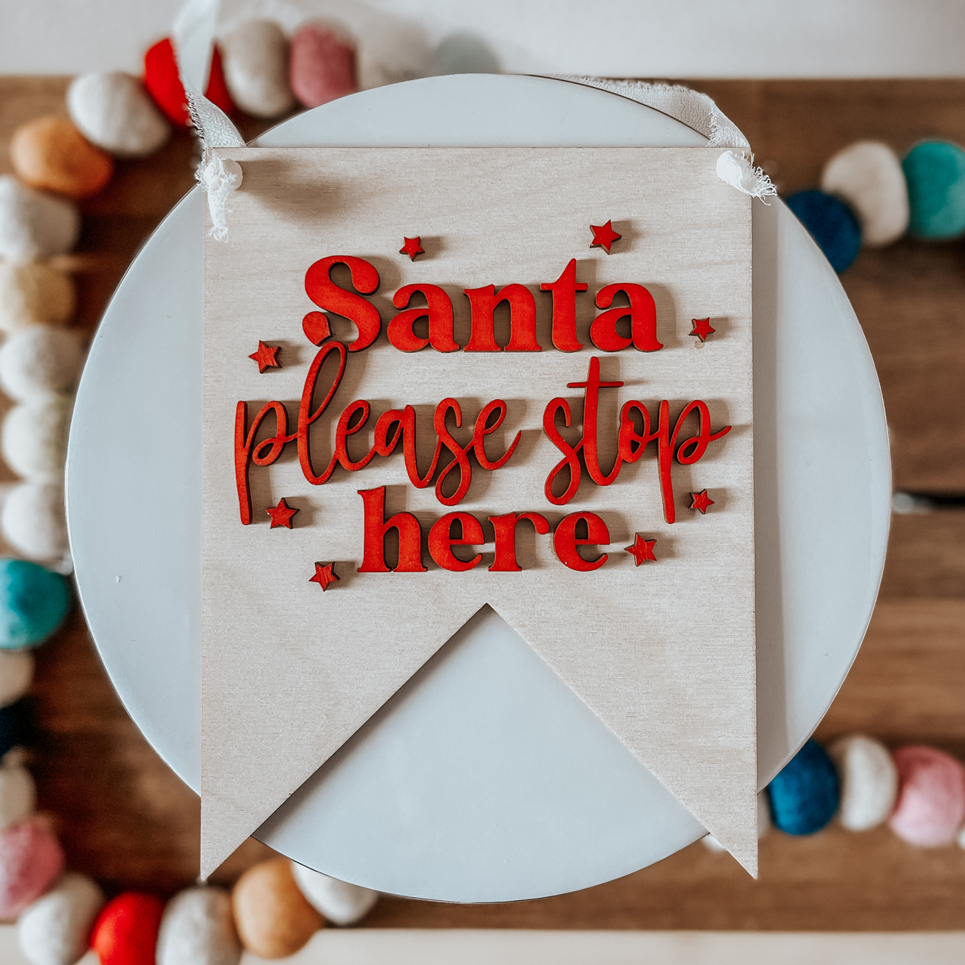 Santa, please stop here wooden pennant sign. Back ground is left natural wood with letters painted Red
