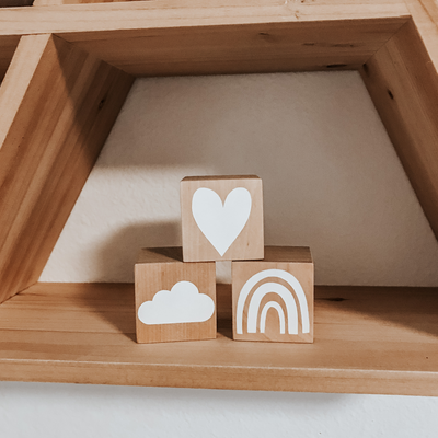 3 natural wood birch blocks with a white heart, white cloud and white rainbow painted on each one
